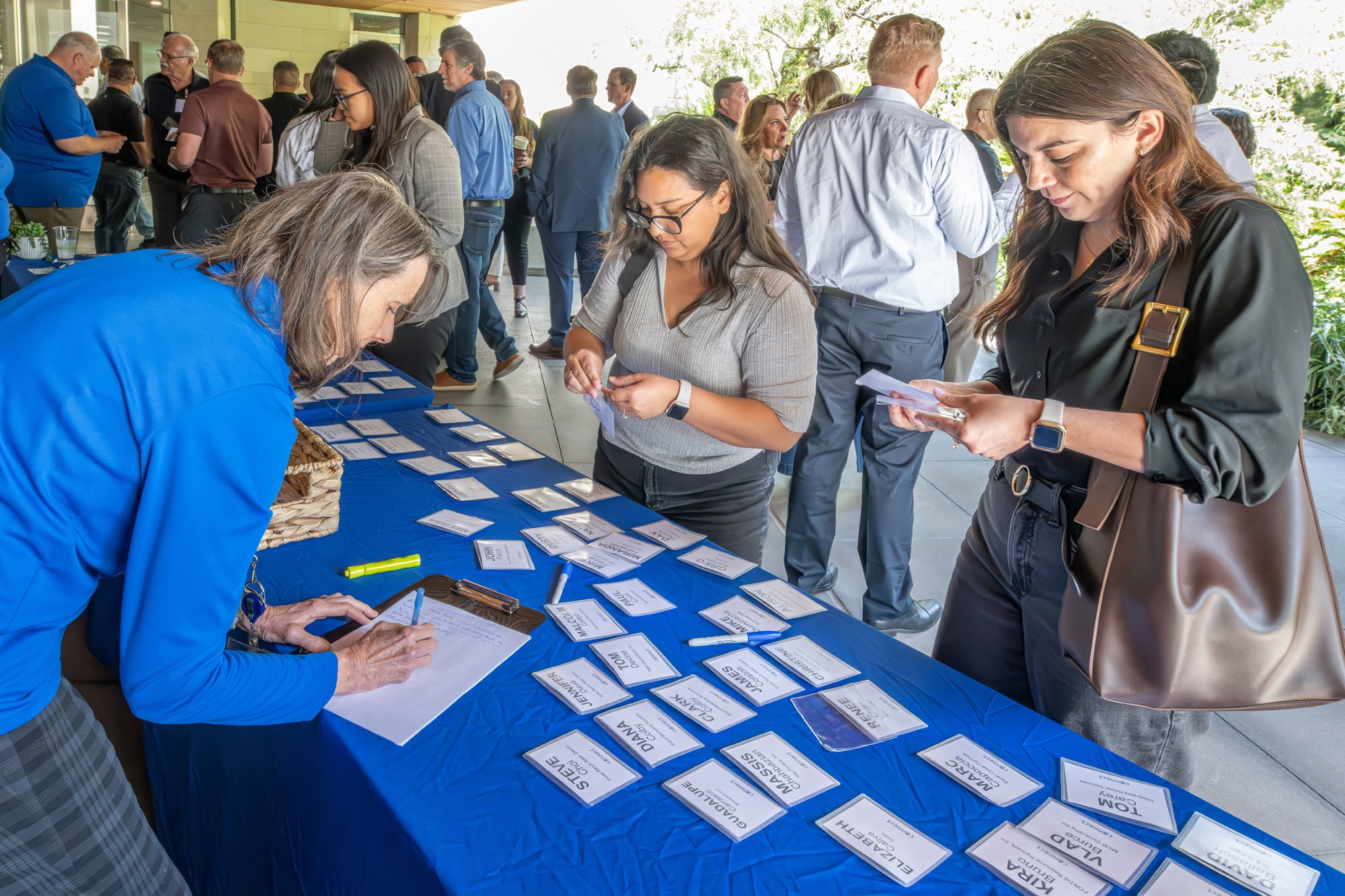 Registration desk at a conference where attendees pick up name badges from a blue-covered table.