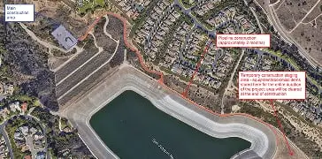 Aerial view of a curved artificial shoreline beside a lagoon-like water body and a residential area.
