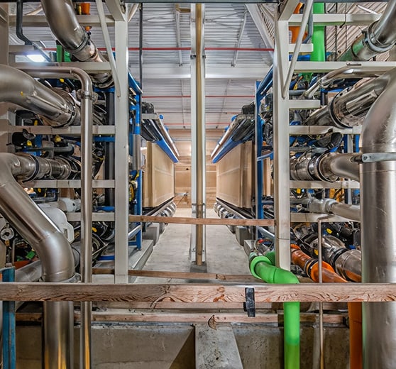 Industrial piping system with dense stainless steel pipes, valves, and metal framing.