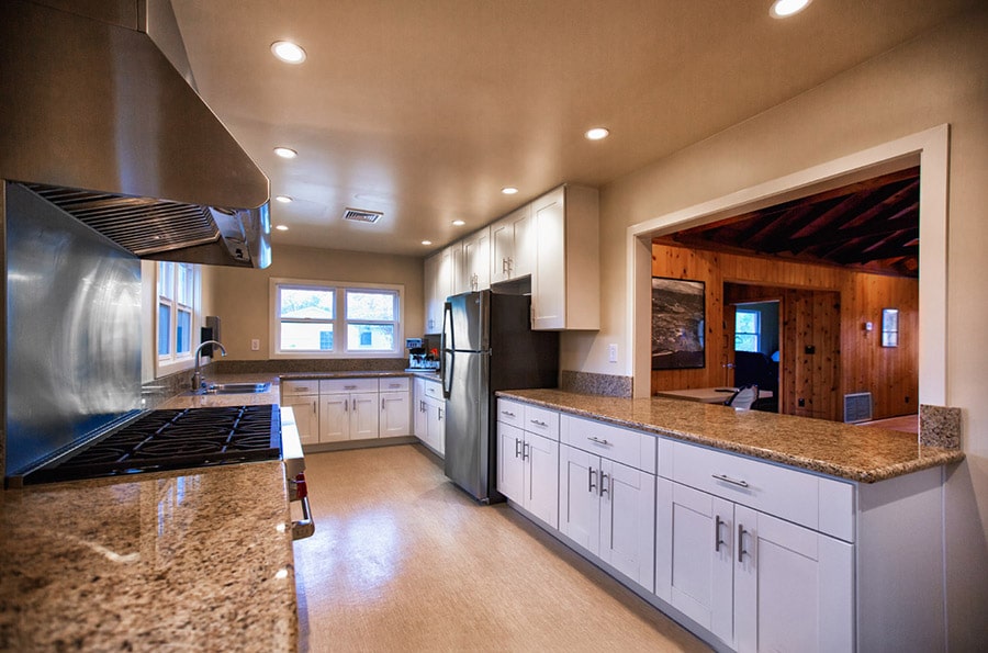 Spacious modern kitchen with white cabinets, granite countertops, and stainless steel appliances.