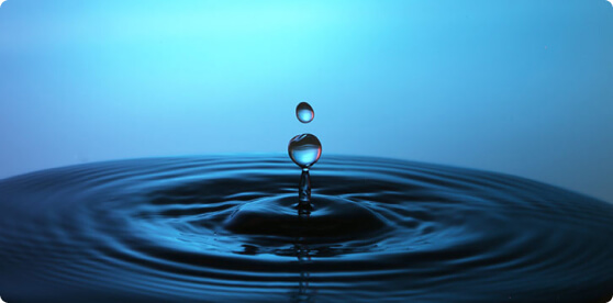 Water droplet creating a ripple on a blue surface