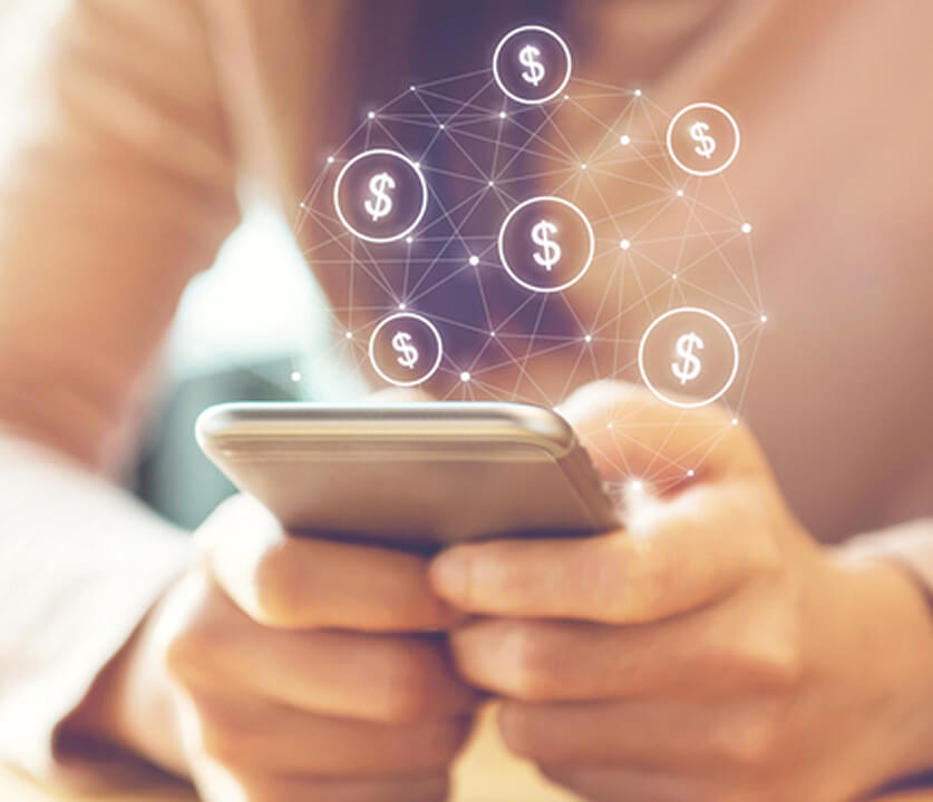 Hands holding a smartphone with a glowing network of dollar symbols orbiting above.
