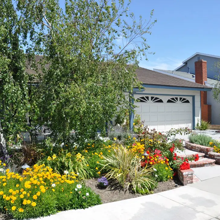 Front yard garden with a variety of colorful flowers beside a suburban house and garage