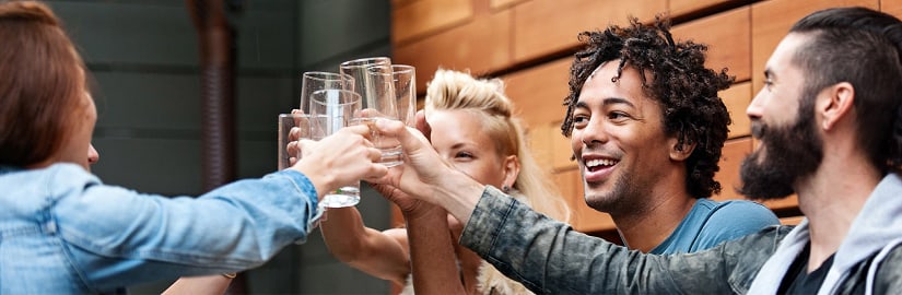 Diverse group of friends toasting with glasses in a casual indoor setting.