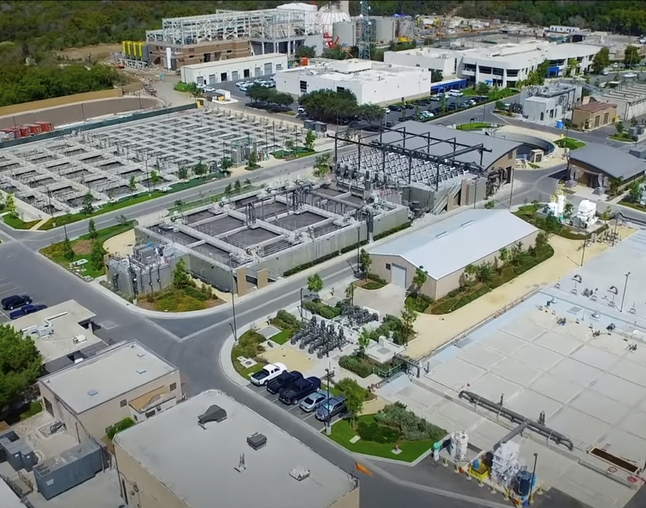 Aerial view of an industrial campus showing electrical substations, transformers, roads, and low-rise buildings.