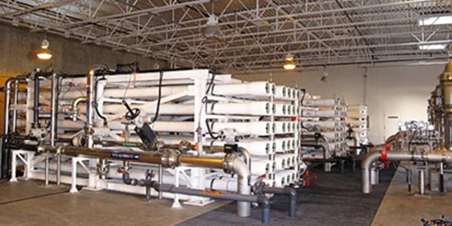 Industrial mechanical room with insulated pipe racks, valves, and pumps