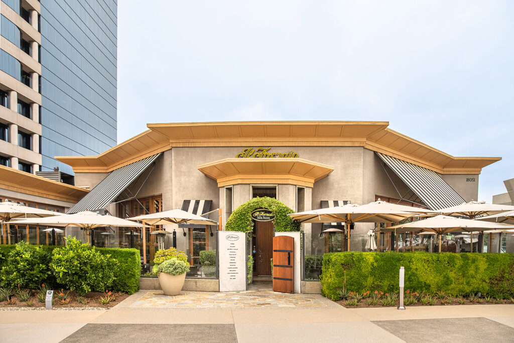 Il Fornaio restaurant entrance with outdoor patio umbrellas and manicured hedges