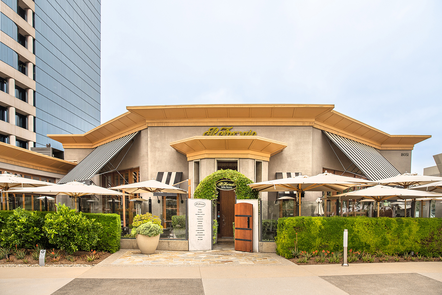 Il Fornaio restaurant entrance with outdoor patio umbrellas and manicured hedges