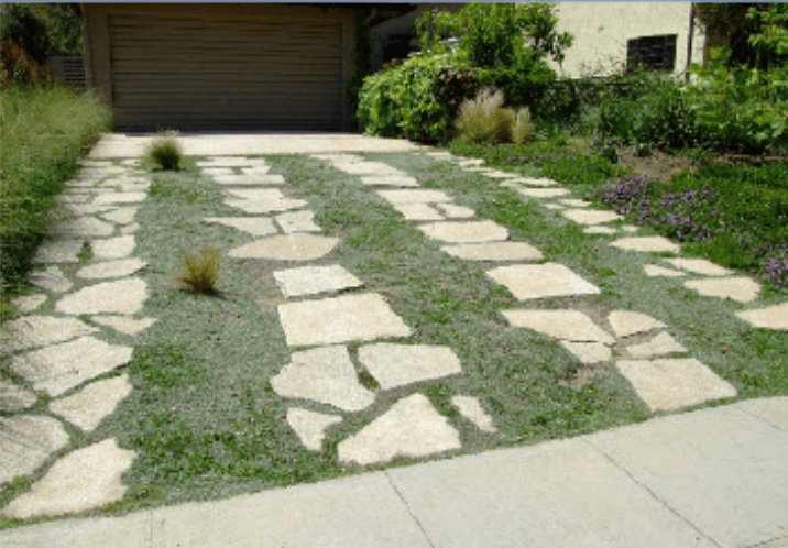 Irregular flagstone path forming a driveway to the garage, with grass and ground-cover between stones.