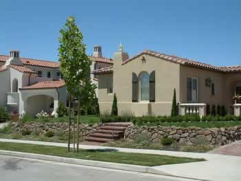 Mediterranean-style suburban home with beige stucco, red tile roof, and landscaped front yard.
